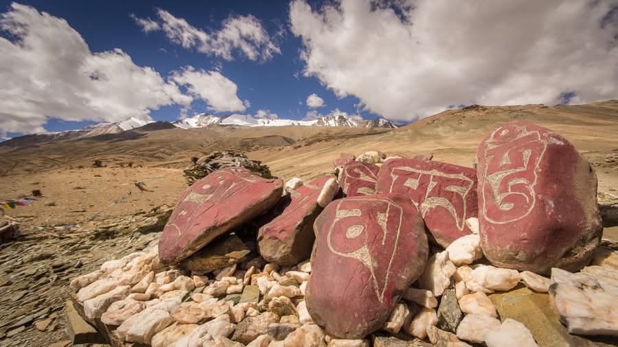 Pierres mani gravées du mantra Om Mani Padme Hum devant les sommets enneigés