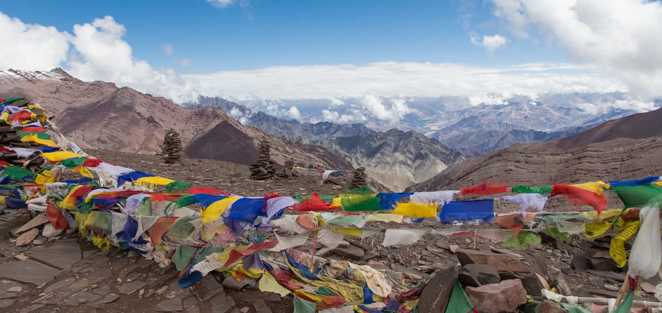 Drapeaux de prières multicolores au sommet d'un col avec panorama sur les montagnes du Ladakh