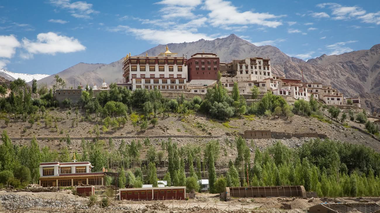 Grand monastère de Spituk entouré de verdure avec les montagnes himalayennes en arrière-plan